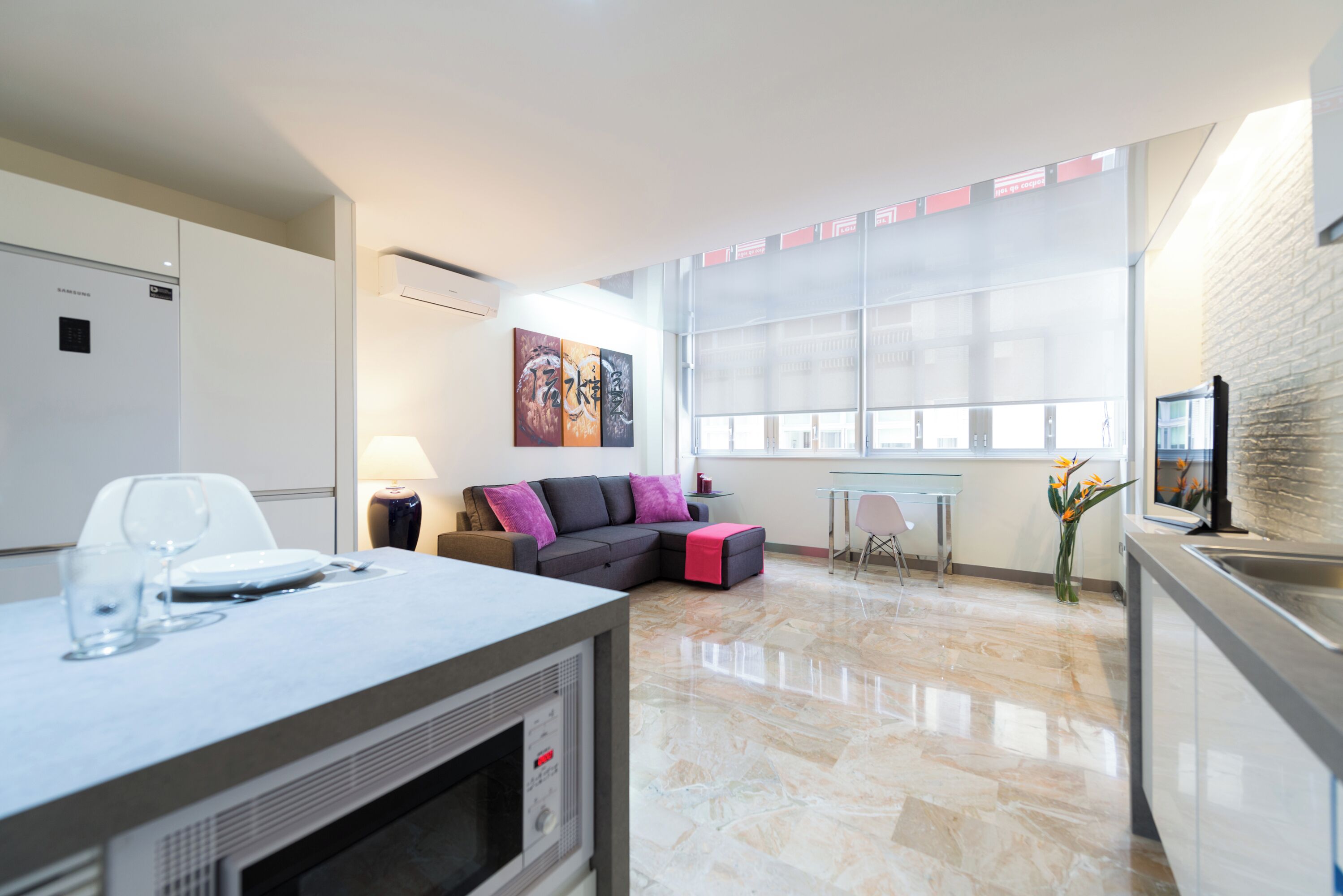 A modern living area with a sofa, a dining table, and a kitchen area.
