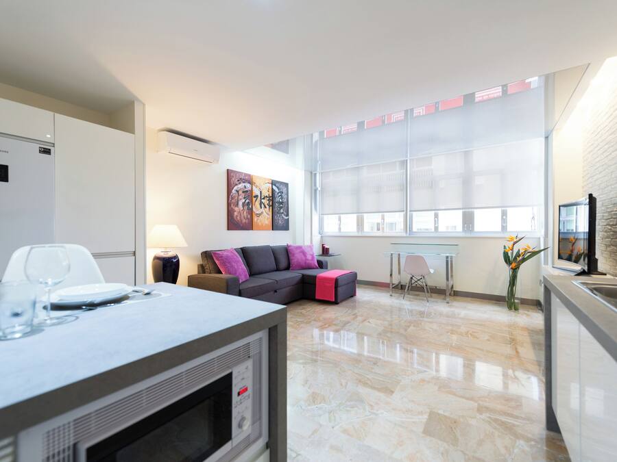 A modern living area with a sofa, a dining table, and a kitchen area.