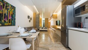 A modern kitchen with a refrigerator, microwave, and a dining area with chairs and a table. - Suites Garden (Las Palmas de Gran Canaria)