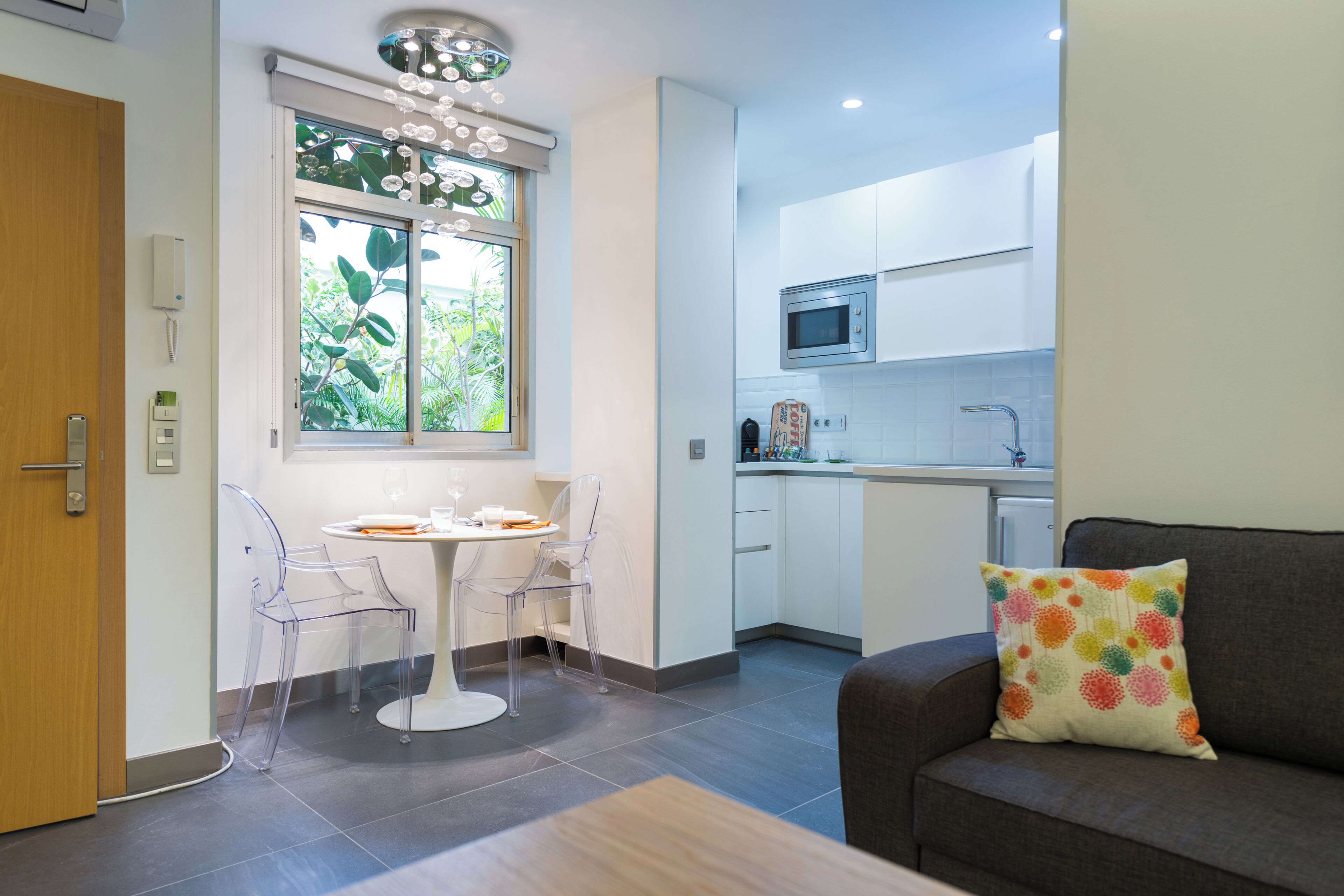 Una cocina moderna con armarios blancos, un microondas y una ventana con vistas a zonas verdes.