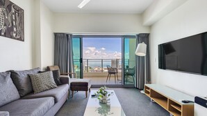 Una sala de estar moderna con sofá, mesa de centro, televisor y balcón con vistas.