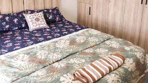 A bedroom with a bed, a wooden wardrobe, and a headboard.