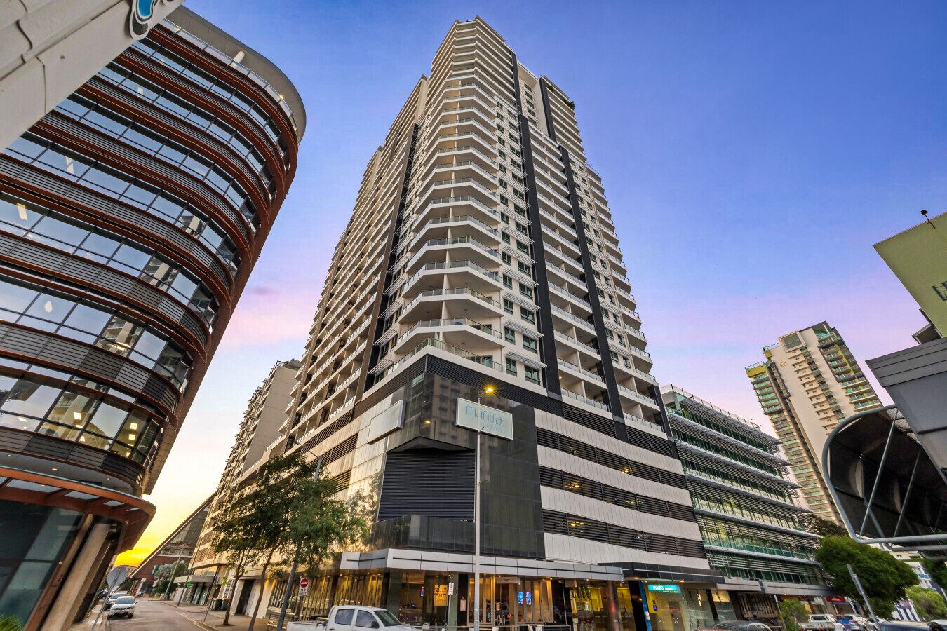 A high-rise building with a modern design, featuring multiple balconies and a prominent entrance.