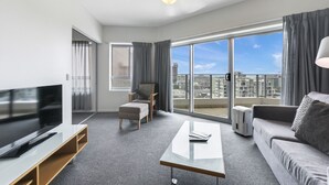 A modern living room with a flat-screen TV, a sofa, a coffee table, and a chair. - Living the Dream on Level 18! (Darwin City)