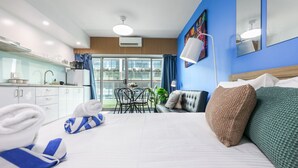 Une chambre d’hôtel avec un lit, un coin repas et une vue dégagée sur l’extérieur grâce à de grandes fenêtres.
