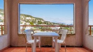 A balcony with a table and two chairs, overlooking a hillside with buildings. - Flat with a balcony offering views of the mountains and the swimming pool (Grasse)