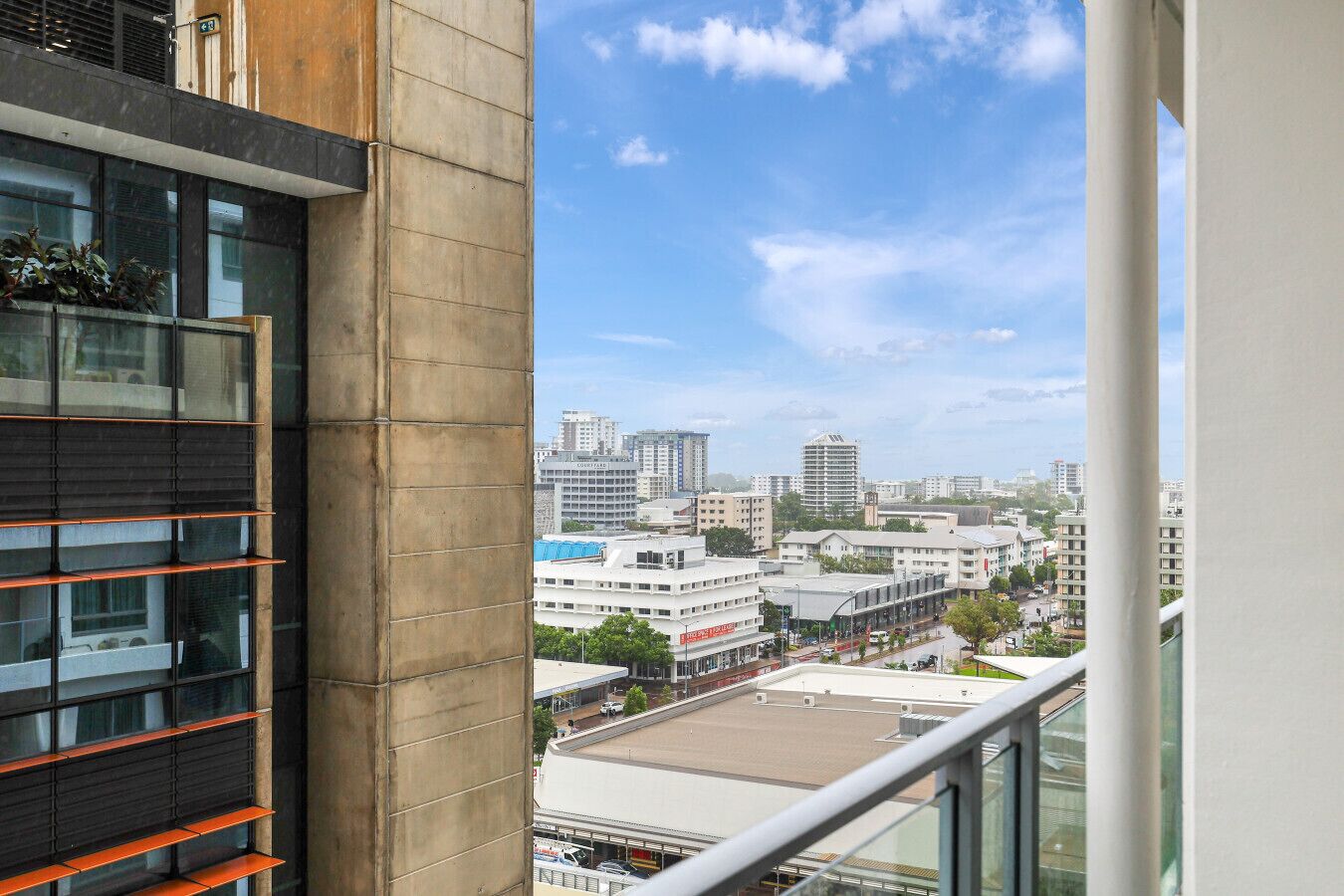 A high-rise building with a view of a cityscape, including various buildings and a clear sky.