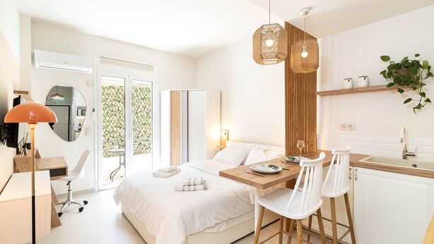 Una habitación de hotel moderna con cama, escritorio, zona de comedor y kitchenette.