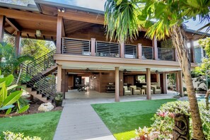 Ein modernes, zweistöckiges Haus mit überdachter Terrasse, einer Treppe und einem gepflegten Garten.