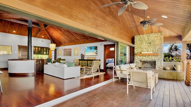 Uma sala de estar ampla, com pé direito alto, piso de madeira e lareira.