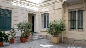 A courtyard with potted plants, a tiled floor, and a building entrance. - Designer Studio steps from Lafayette (Paris)