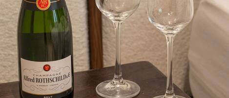 A bottle of Alfred Rothschild champagne and two empty glasses on a wooden table.