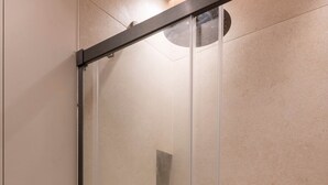A modern shower enclosure with a glass door, a handheld showerhead, and a wall-mounted control panel. - Designer Studio steps from Lafayette (Paris)