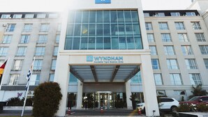 A modern building with a glass facade, a prominent WYNDHAM logo, and a series of windows.