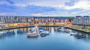 A marina with boats docked, surrounded by multi-story buildings with balconies.