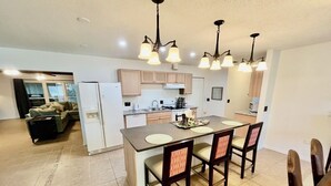 A modern kitchen with a central island, dining area, and a living room.