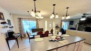 A kitchen with a large island, pendant lights, a dining area with chairs, and a stone fireplace.