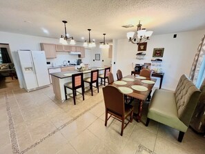 A modern kitchen with a central island, dining area with chairs and a table, and a sofa. - 4 bedroom pool house located in a bird sanctuary (Hudson)