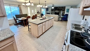 A spacious kitchen with a central island, granite countertops, and a dining area with a chandelier.