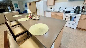 A kitchen with a dining table, chairs, a refrigerator, a stove, and cabinets.