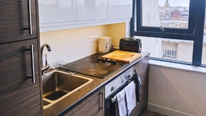Een moderne keuken met een spoelbak, fornuis en broodrooster, en een raam met uitzicht op de stad.