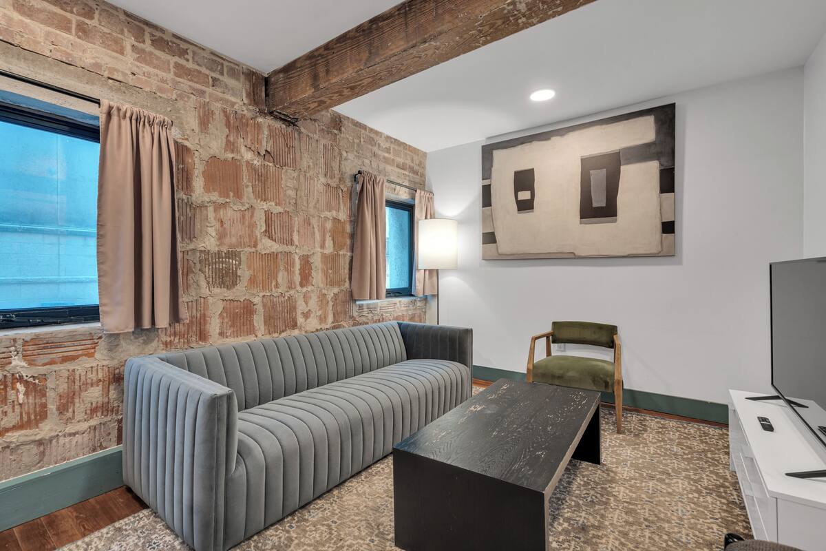 A modern living room with a sofa, a coffee table, a TV, and a lamp.