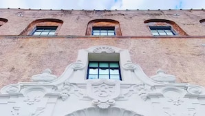 A building facade with a large arched window and the name 'SCHAEFFER' illuminated above it. - Schaeffer Hotel (New Orleans)