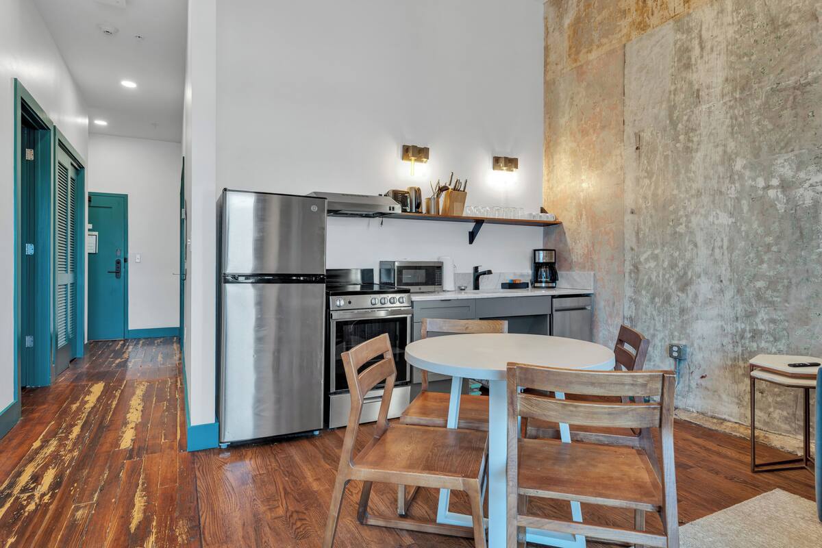 A modern kitchen with stainless steel appliances, a wooden dining table, and chairs.