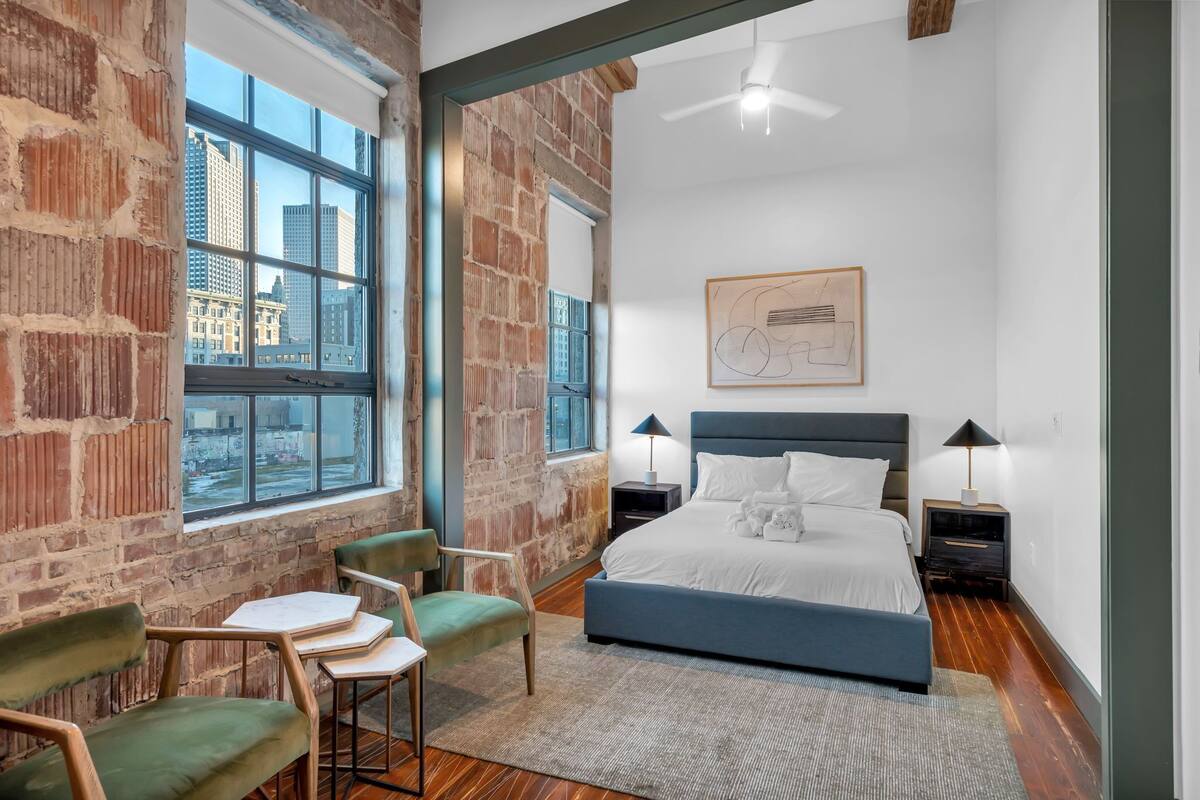 A modern bedroom with a large window, a bed, a desk, and a chair.