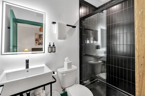 Een badkamer met een wit wastafel, toilet, spiegel en een douchecabine.