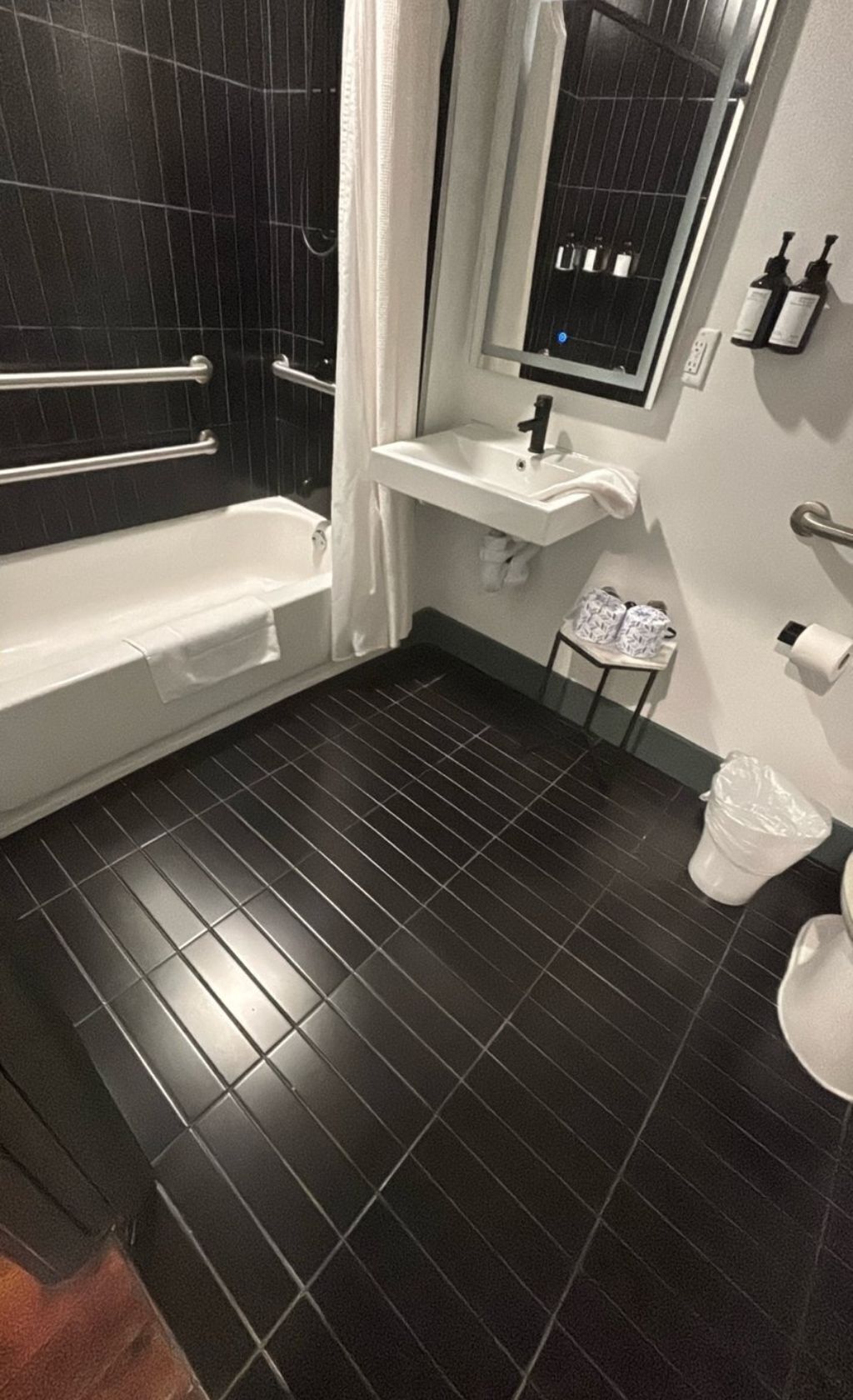 A bathroom with a bathtub, a sink, a mirror, and a toilet.