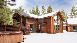 En træhytte med stor terrasse, jacuzzi og trappe op til en anden etage.