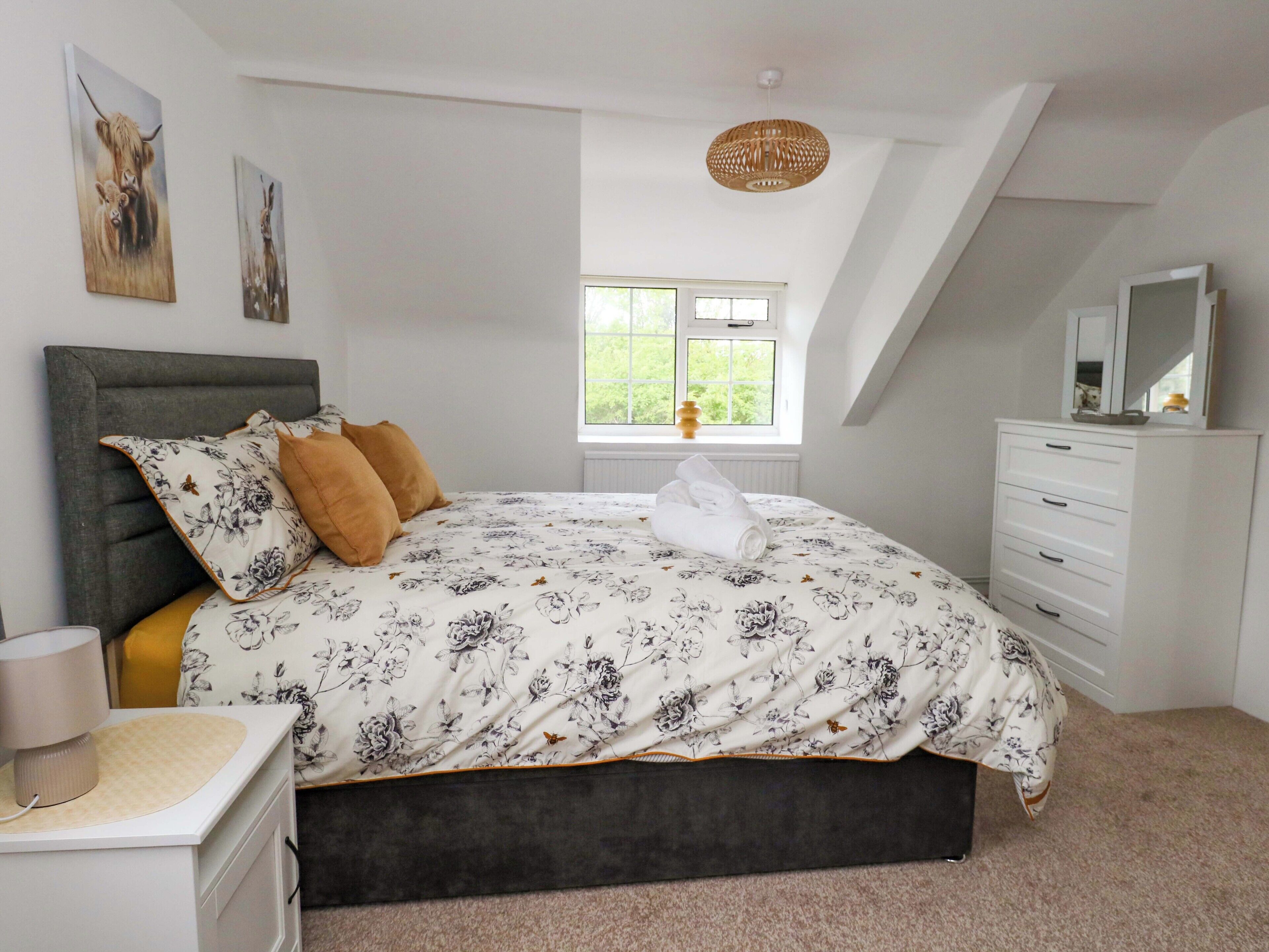 Une chambre à coucher comprenant un lit, une table de chevet, une commode, une fenêtre avec vue et un luminaire au plafond.