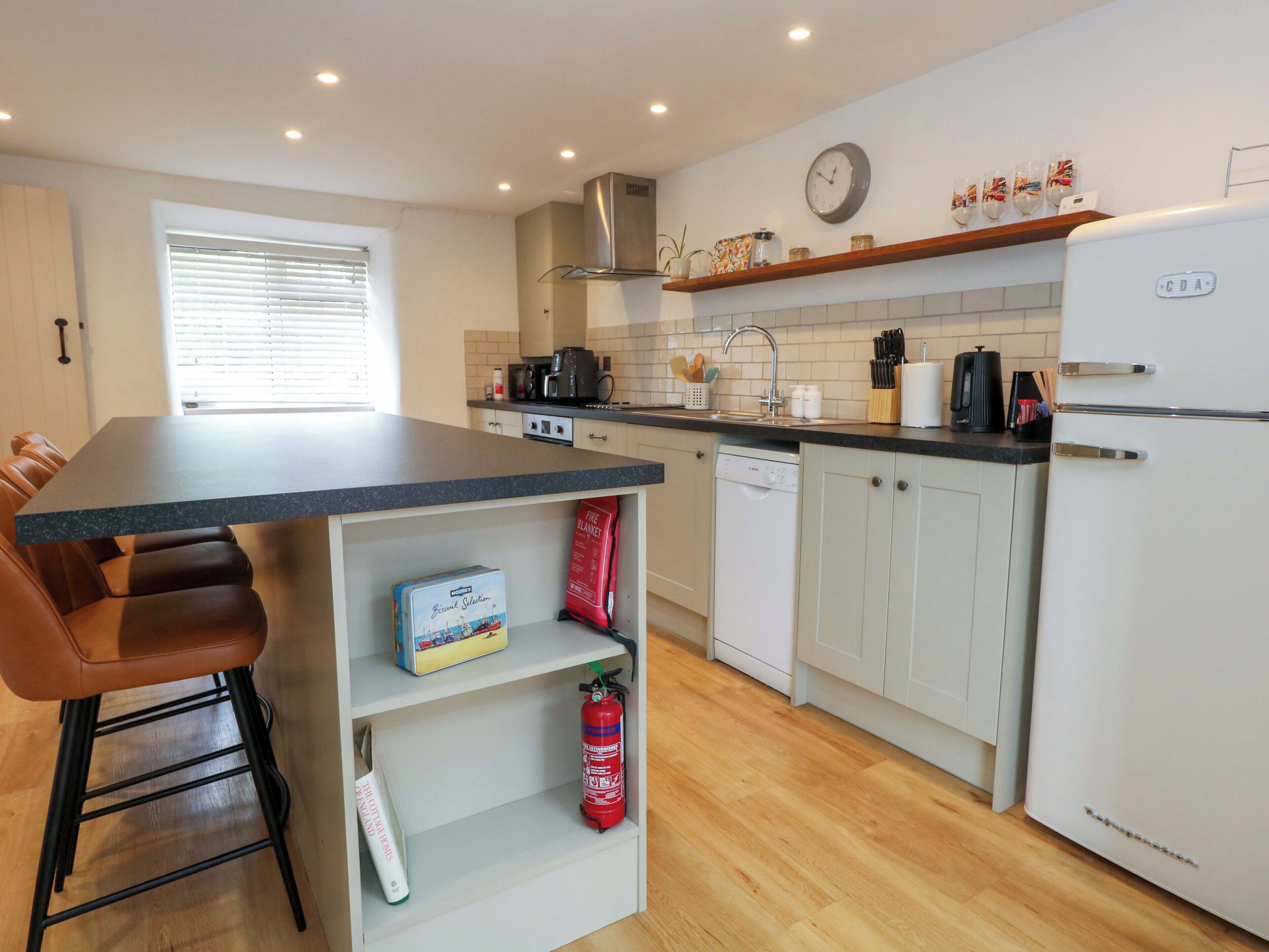 A modern kitchen with a central island, a dishwasher, and a refrigerator.