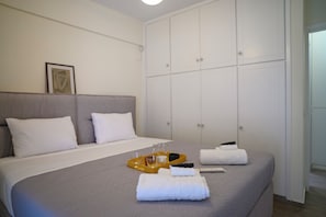 A hotel room with a bed, a wardrobe, and a framed picture on the wall. - Premium 1bdr Temple of Peacefulness (Athina)
