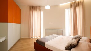 Een slaapkamer met een bed, gordijnen, een kledingkast en een plafondlamp.