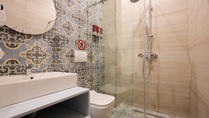 Een badkamer met douche, toilet en wastafel.