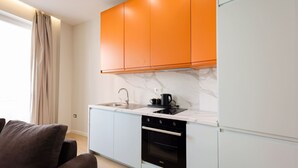 Een moderne keuken met witte kasten, een zwarte oven en een marmeren aanrecht.