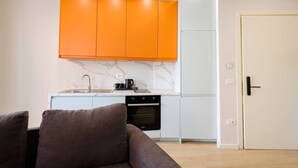 Een moderne keuken met witte kasten, een marmeren spatwand en een inbouwoven.