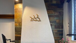 A fireplace with a stone accent wall, a wooden mantel, and a decorative metal piece above it. - Cozy Home in Cholargos (Cholargos)