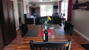 Un coin repas avec une table en bois, des chaises, un vase de fleurs et un luminaire suspendu.