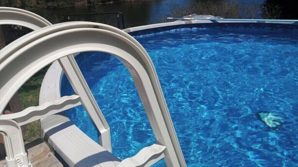 Une piscine avec vue sur un lac et des arbres.