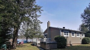 Une maison de plain-pied avec un patio couvert, une cheminée et une petite terrasse.