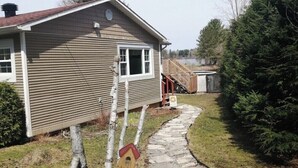 Une maison avec un chemin de pierre menant à une terrasse en bois.