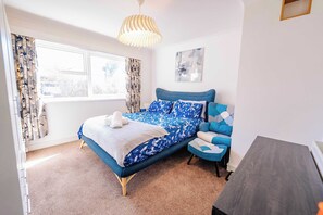 A bedroom with a bed, a chair, a table, a window with curtains, and a ceiling light. - Cozy 2-Bed, 1-Bath with Free Parking, Close to Roath Park (Caerdydd)