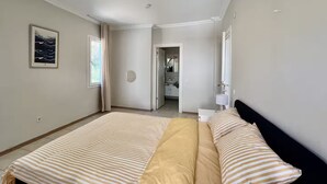 A bedroom with a bed, a nightstand, a mirror, and a bathroom visible through an open door. - Lacivert Apart - Modern House with 180 Degree Unique Kaş View (Gazi)