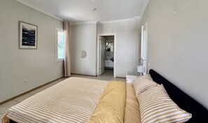 Ein Schlafzimmer mit Bett, Nachttisch, Spiegel und angrenzendem Badezimmer.