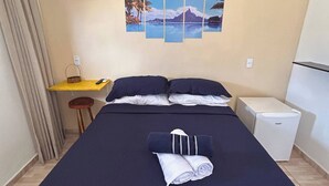 Une chambre d’hôtel équipée d’un lit, d’un bureau, d’une chaise, d’un petit réfrigérateur et d’un mur orné d’une grande image panoramique.