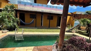 Una casa con piscina, hamaca y jardín con plantas.