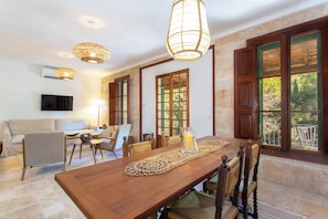 A dining area with a wooden table, chairs, a woven placemat, and a hanging light fixture. - Villa with Sea and Mountain Views + Pool (Illes Balears)